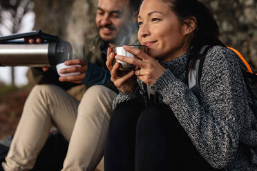 Junges Paar macht eine Pause auf einer Wanderung. Mann und Frau trinken Kaffee beim Wandern. - JLPSF27503