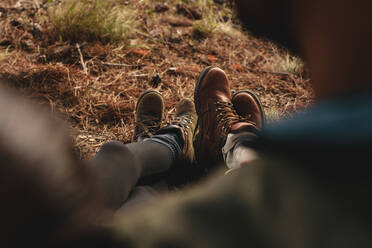 Close up of couple of hikers sitting together outdoors, focus on legs. Hikers resting on country trail. - JLPSF27520