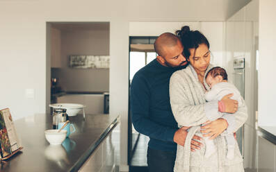 Junger Vater und Mutter halten ihren kleinen Jungen in der Küche. Eltern verbringen Zeit mit ihrem neugeborenen Sohn zu Hause am Morgen. - JLPSF27529