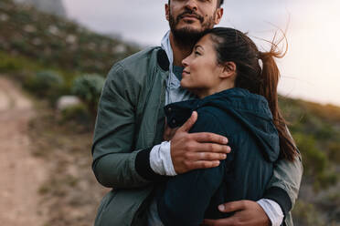 Romantic young couple embracing during hike in countryside. Loving young man and woman in countryside - JLPSF27546