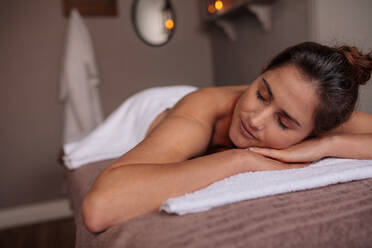 Woman lying on a table with eyes closed in a wellness center. Attractive female lying on a spa table with eyes closed in a health spa. - JLPSF27745