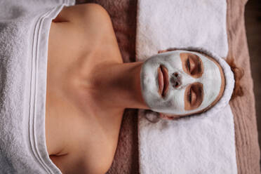 Top view of woman wearing facial mask lying on spa table. Beautiful young woman getting facial mask in spa. - JLPSF27775