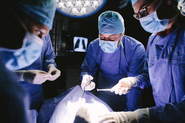 Ärzte bei einer Operation im Krankenhaus. Ein Team von professionellen Chirurgen arbeitet im Krankenhaus und führt einen chirurgischen Eingriff im Operationssaal durch. - JLPSF27780