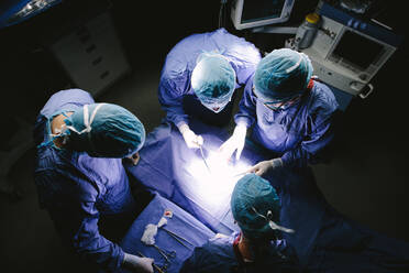 Top view shot of team of surgeons performing surgery in operation theater. Group of doctors in hospital operating theatre. - JLPSF27781