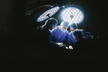 Professional medical team performing surgery in hospital. Group of surgeons at work in operation theater. - JLPSF27786