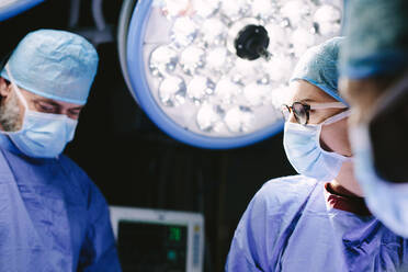 Surgeons wearing medical mask performing surgery in operation theater. - JLPSF27790