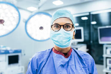 Close up Porträt der weiblichen Chirurgin trägt chirurgische Maske und Kittel im Operationssaal. Professionelle medizinische bereit für den Betrieb im Krankenhaus. - JLPSF27796