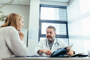 Männlicher Arzt im Gespräch mit einer Patientin. Medizinischer Facharzt im Gespräch mit einer Patientin während einer Konsultation in der Praxis. - JLPSF27801