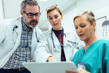 Medical staff discussing over medical reports. Healthcare professionals having discussion in hospital corridor. - JLPSF27817