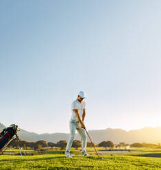 Männlicher Golfer in voller Länge, der auf dem Golfplatz steht und abschlägt. Professioneller Golfspieler spielt an einem sonnigen Tag. - JLPSF27823