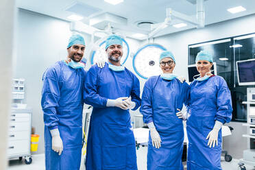 Portrait of successful team of surgeon standing in operating room, ready to work on a patient. Medical workers in surgical uniform in operation theater. - JLPSF27862