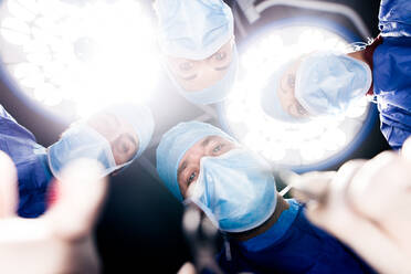 Team of surgeons operating under surgery lights in operation theater. Point of view shot of dentists performing dental surgery in hospital. - JLPSF27872