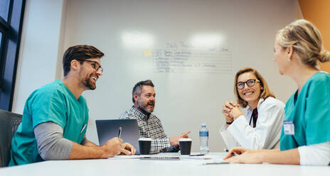 Glückliches medizinisches Team bei einer Besprechung im Konferenzraum im Krankenhaus. Ärzte bei der Besprechung im Krankenhausbüro. - JLPSF27891