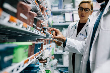 Two pharmacists checking inventory at hospital pharmacy. Hospital staff stocktaking in drugstore. - JLPSF27910