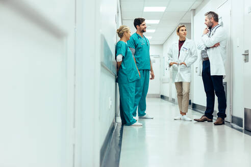 Eine Gruppe von medizinischem Personal diskutiert auf dem Flur einer Klinik. Fachkräfte des Gesundheitswesens diskutieren auf dem Krankenhausflur. - JLPSF27919
