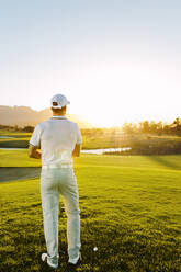 Rückansicht eines jungen männlichen Golfspielers am Abschlagplatz auf dem Golfplatz. - JLPSF27923