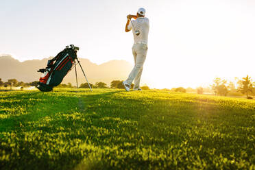 Low angle shot of professional golfer taking shot while standing on field. full length of golf player swinging golf club on sunny day. - JLPSF27927