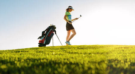 Aufnahme einer professionellen Golferin auf dem Golfplatz in voller Länge mit Golfschläger auf dem Feld. - JLPSF27936