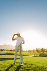 Junger Mann in voller Länge auf dem Golfplatz stehend, Profigolfer hält Golfschläger auf dem Feld. - JLPSF27943