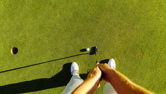 Pov-Aufnahme eines Golfspielers auf dem Putting Green, der den Ball in ein Loch schlägt. Persönliche Perspektive eines professionellen Golfspielers, der auf einem Feld Golf spielt. - JLPSF27954