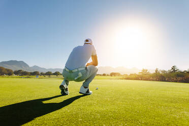 Rückansicht eines Golfspielers, der einen Schlag auf dem Golfplatz anvisiert. Profigolfer auf dem Feld während des Spiels. - JLPSF27955