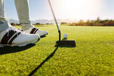 Männlicher Golfer auf dem Putting Green kurz vor dem Schlag. Golfspieler, der den Golfball ins Loch schlägt. - JLPSF27957