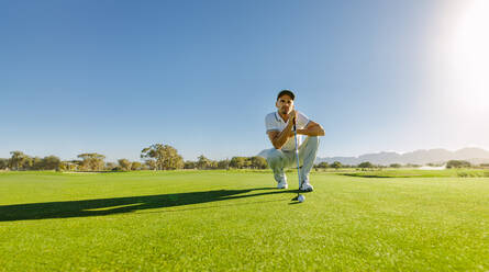 Profi-Golfspieler, der mit dem Schläger auf dem Golfplatz zielt. Männlicher Golfer auf dem Putting-Green, der den Schlag ausführen will. - JLPSF27962