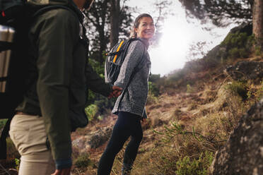 Junge Frau mit ihrem Freund auf einem Spaziergang durch die Landschaft. Glückliches junges Paar beim gemeinsamen Wandern. - JLPSF28000