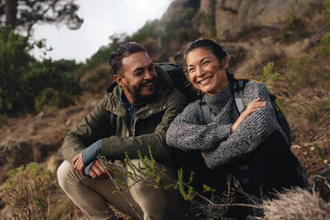 Young couple taking a break on a hike. Happy young man and woman sitting on mountain trail. - JLPSF28001