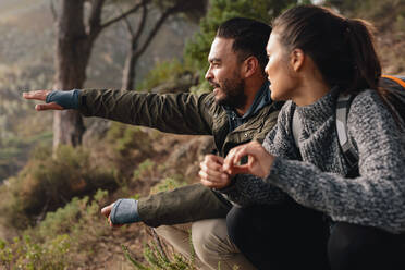 Young couple relaxing, with man showing something to woman. Young couple hiking on mountains. - JLPSF28003