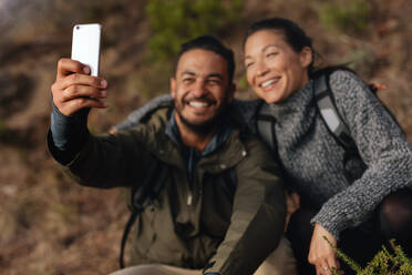 Junges Paar beim Wandern nimmt Selfie mit Smartphone. Glücklicher junger Mann und Frau nehmen Selbstporträt. - JLPSF28007