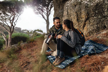 Ein Wandererpaar macht eine Kaffeepause am Hang eines Berges. Ein junger Mann und eine Frau sitzen zusammen und trinken Kaffee, ein Paar wandert auf einem Berg. - JLPSF28008