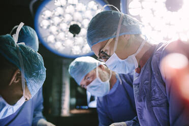 Concentrated female surgeon performing surgery with her team in hospital operating room. Medics during surgery in operation theater. - JLPSF28027