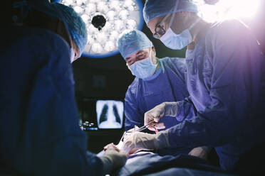 Medical team performing surgical procedure in operating theater. Professional surgeons performing surgery in operating room of a hospital. - JLPSF28028