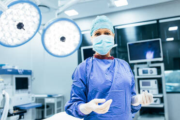 Porträt eines Chirurgen, der im Operationssaal steht und bereit ist, an einem Patienten zu arbeiten. Weiblicher medizinischer Mitarbeiter in chirurgischer Uniform im Operationssaal. - JLPSF28041