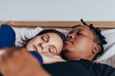 Mixed race couple sleeping together in bed. African man sleeping with caucasian woman at home. - JLPSF28057