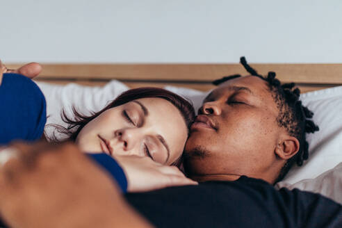 Gemischtrassiges Paar schläft zusammen im Bett. Afrikanischer Mann schläft mit weißer Frau zu Hause. - JLPSF28057