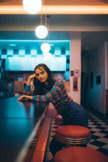 Beautiful young woman standing by bar counter. Female in 90s style fashion  in pub. stock photo