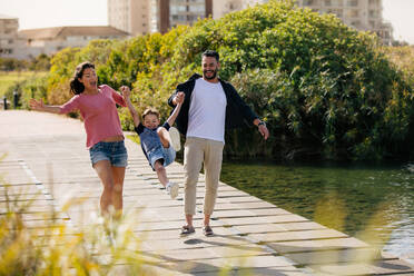 Happy couple in playful mood outdoors enjoying with their child. Cheerful family on vacation enjoying outdoors. - JLPSF28094