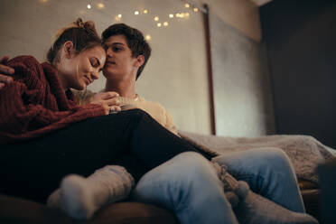 Gemütliches Paar sitzt zusammen auf der Couch zu Hause. Romantischer Mann und Frau entspannen im Wohnzimmer. - JLPSF28099
