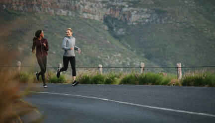 Two women going for an early morning run. Fitness runners in track suits running on road. - JLPSF28118