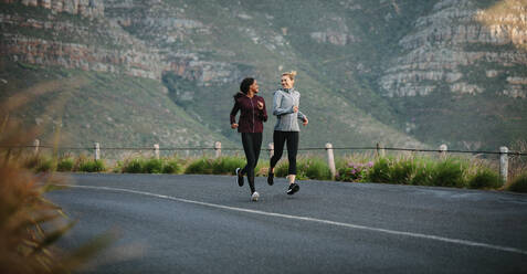 Zwei Frauen beim morgendlichen Lauf: Fitnessläuferinnen in Trainingsanzügen laufen auf der Straße. - JLPSF28119
