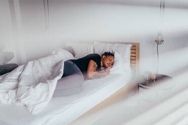 Afrikanischer Mann schläft im Schlafzimmer mit einer Frau im Rücken, ein Paar schläft Rücken an Rücken auf dem Bett. - JLPSF28160