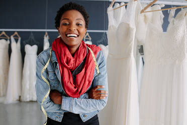 Portrait of african female bridal store owner standing with her arms crossed and smiling. Woman tailor standing in wedding fashion shop. - JLPSF28181