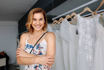 Schöne junge Braut steht in einer Braut Boutique. Lächelnde Frau Einkaufen für Hochzeit Outfit in Braut Kleidung zu speichern. - JLPSF28192