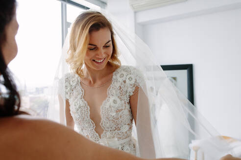 Schöne junge Frau versucht auf Hochzeitskleid in Brautladen mit Assistent. Zukünftige Braut Anprobe neues Kleid in Hochzeit Mode-Shop. - JLPSF28205