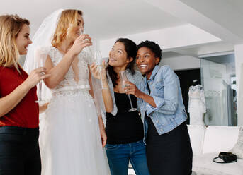 Frau im Hochzeitskleid trinken Champagner mit Freunden in Braut-Boutique. Schöne Braut in eleganten Hochzeitskleid und Freunde mit Champagner in Hochzeit Mode-Shop. - JLPSF28211