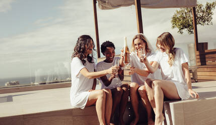 Happy young women drinking champagne at bachelorette party on rooftop. Bride and bridesmaid having fun at hen party. - JLPSF28234