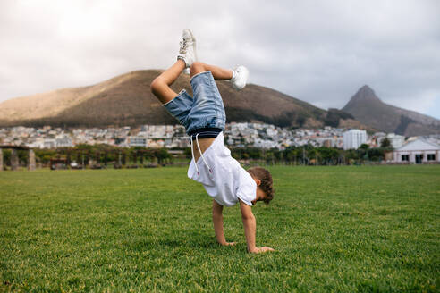 Boy balancing on hands in upside down position in a ground. Boy playing acrobatically in a ground. - JLPSF28248