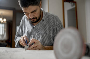 Handwerker beim Schneiden von Holz mit einer Hexablade zu Hause - ANAF00443